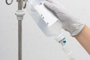 vertical-shot-medical-person-holding-infusion-bag-hung-metal-hanger (1)
